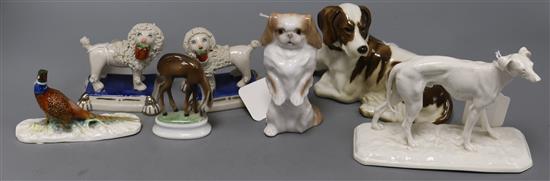 A pair of Staffordshire poodles standing on plinth bases and various animal models,